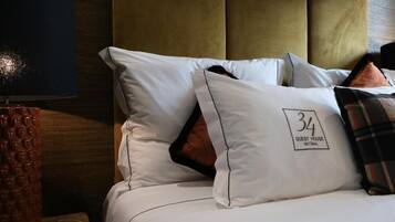 A hotel room with a bed, pillows, and a lamp.