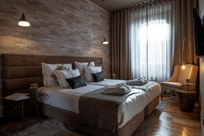 A modern hotel room with a large bed, a seating area, and a television. - 34 Guest House (Setubal)