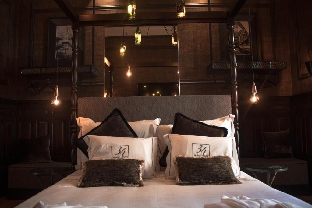 A hotel room with a large bed, two pillows with numbers, hanging light bulbs, and a wooden headboard.