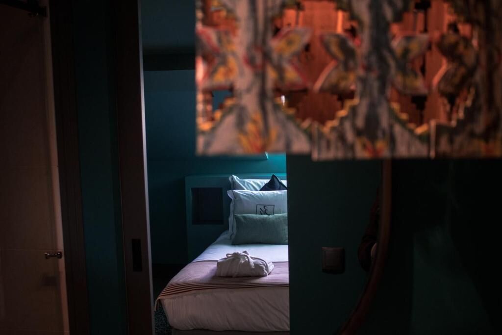 A hotel room with a bed, a nightstand, and a wall with a decorative pattern.