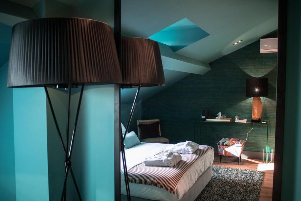 A modern bedroom with a large bed, a bedside table, a chair, and a floor lamp.