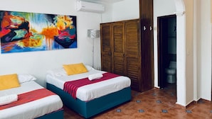 A hotel room with two beds, a colorful abstract painting, a wooden wardrobe, and a bathroom visible through an open door. - Beautifull Apartment beach front & nice sea view (Cancun)