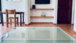 A room with a glass-top pool, a wooden chair, a TV mounted on the wall, and a wooden door. - Beautifull Apartment beach front & nice sea view (Cancun)