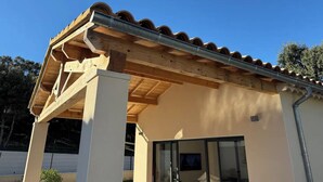 A modern building with a wooden pergola structure, large windows, and a tiled roof. - Maison "les Chênes D'hélios" en Drôme Provençale - Logement Entier (Réauville)