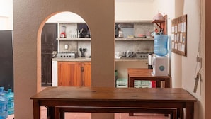 Une cuisine avec une table en bois, un distributeur d’eau et des placards.