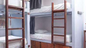 Quarto estilo dormitório com beliches, escadas de madeira e uma pequena mesa.