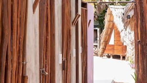 Une porte en bois, dotée d’un loquet métallique, qui donne accès à une construction dont le toit est fait de chaume.