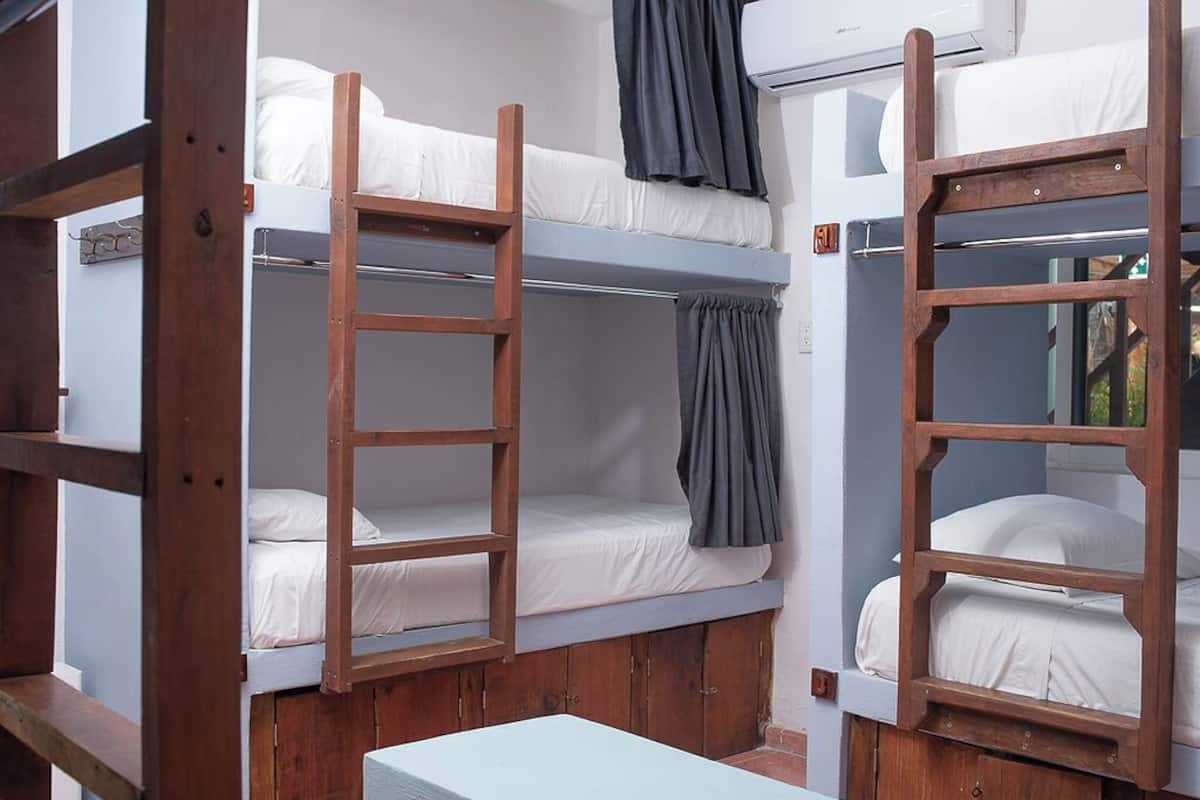 A dormitory-style room with bunk beds, wooden ladders, and a small table.