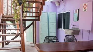 A wooden staircase leading to a room with a purple wall, a sink, and two green lockers.