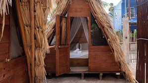 Une hutte au toit de chaume, avec un lit à l’intérieur.