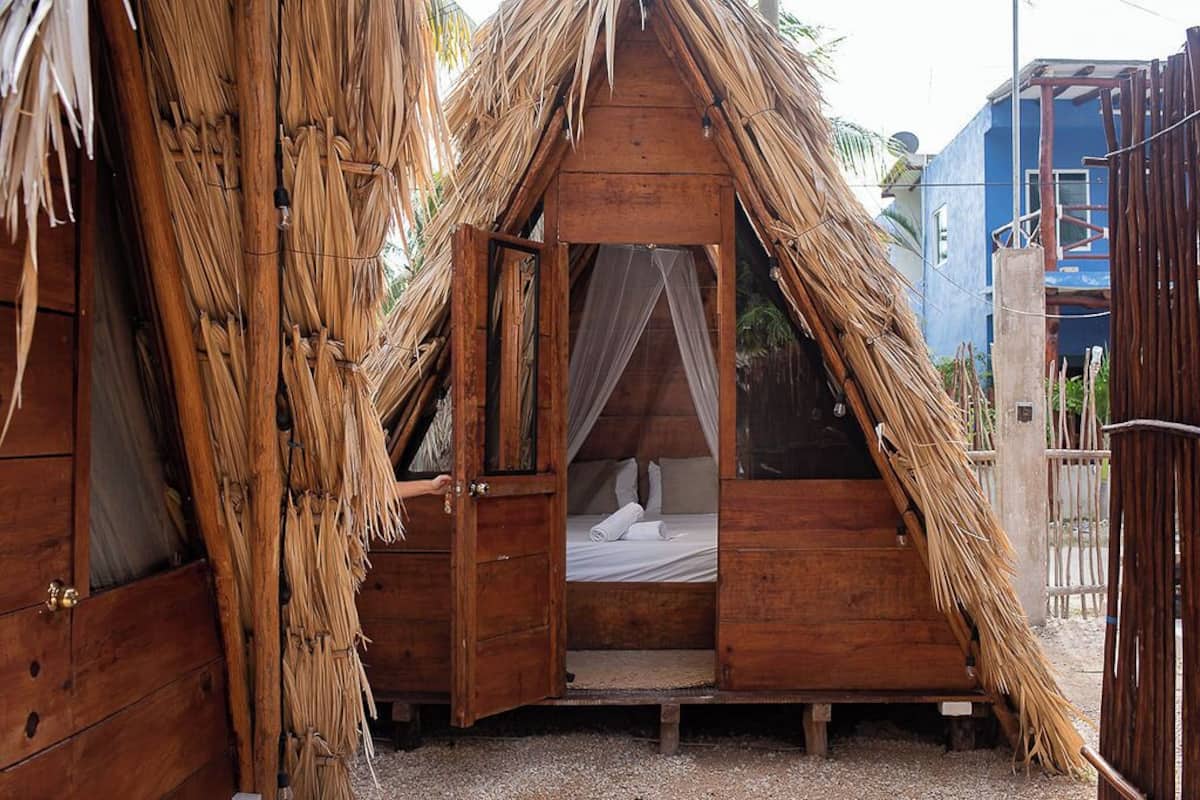 A thatched-roof hut with a bed inside.
