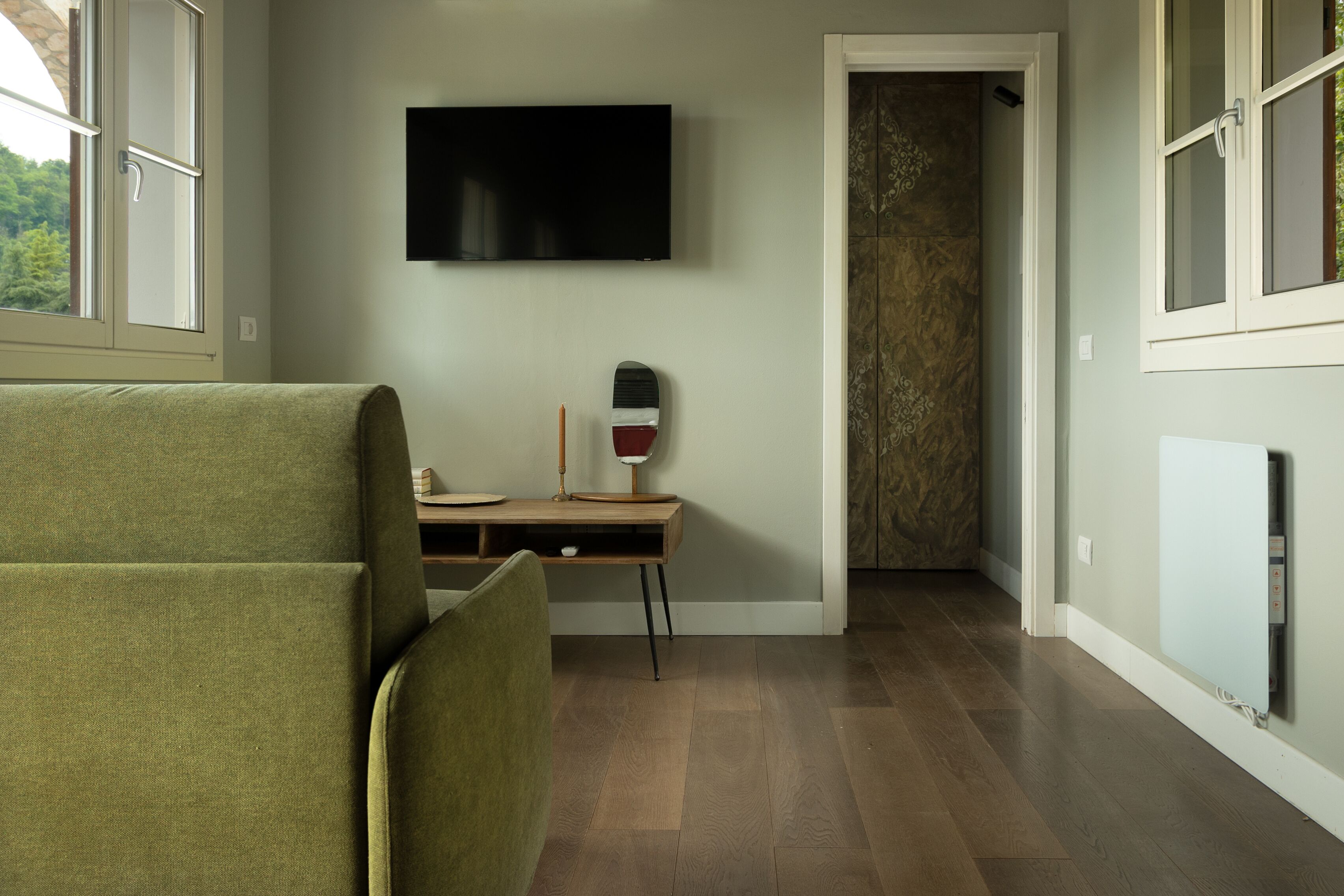 Een kamer met een groene bank, een houten bureau, een flatscreen televisie en een kamer met een patroon.
