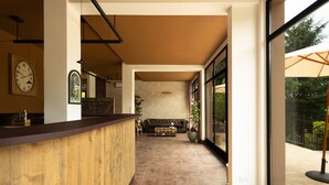 A reception area with a wooden counter, a couch, and a large window offering a view of the outdoors. - Luce Boutique Hotel (Fortunago)