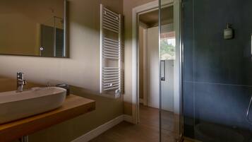 Un baño con un lavabo grande, un espejo, toallero y zona de ducha.