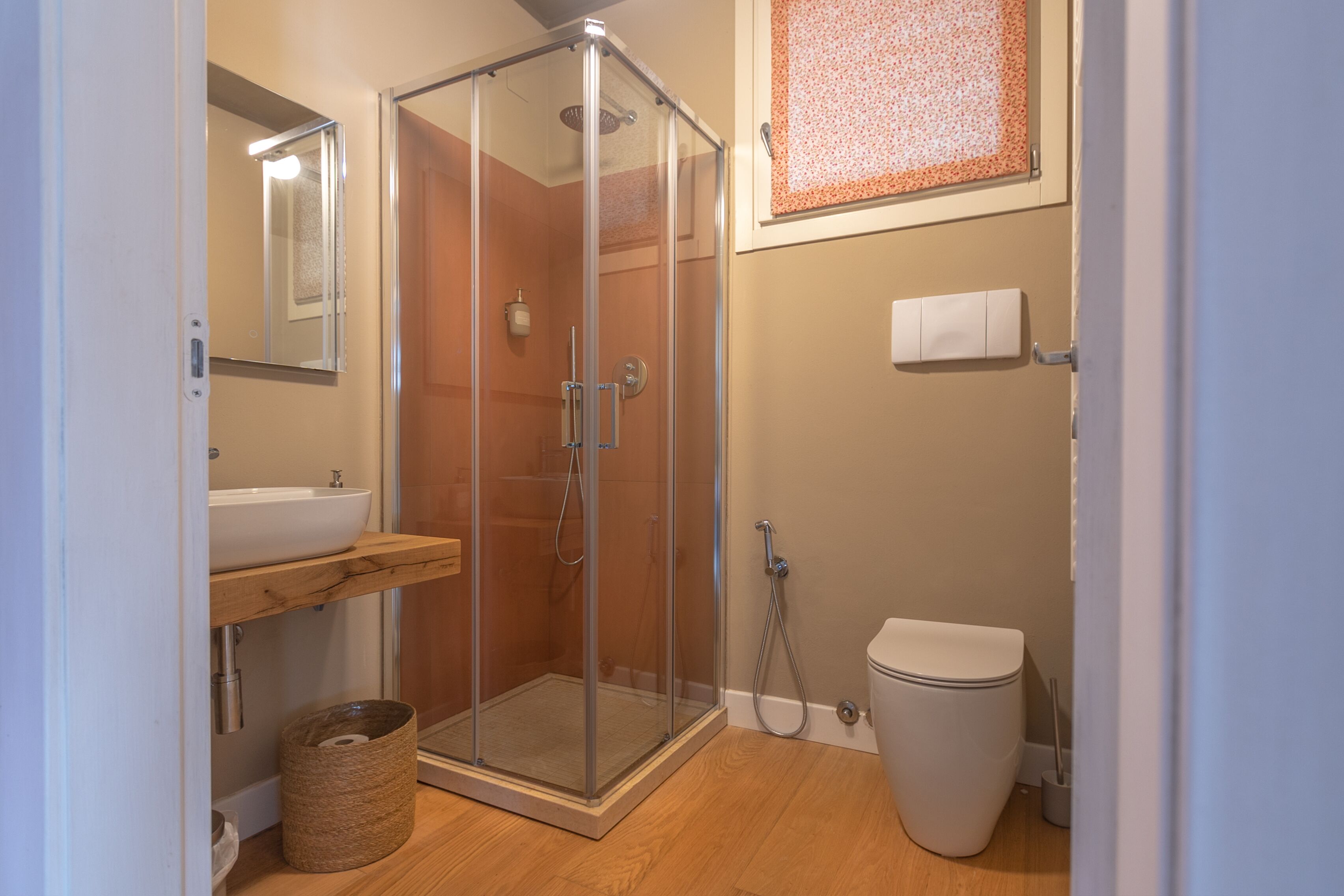 Ein modernes Badezimmer mit einer Duschkabine, einem Holzwaschtisch, einem weißen Waschbecken und einer Toilette.