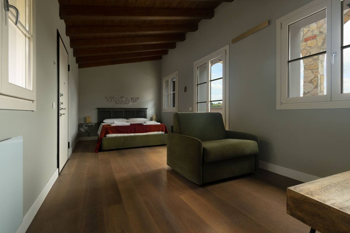 A bedroom with a bed, a chair, and a desk.