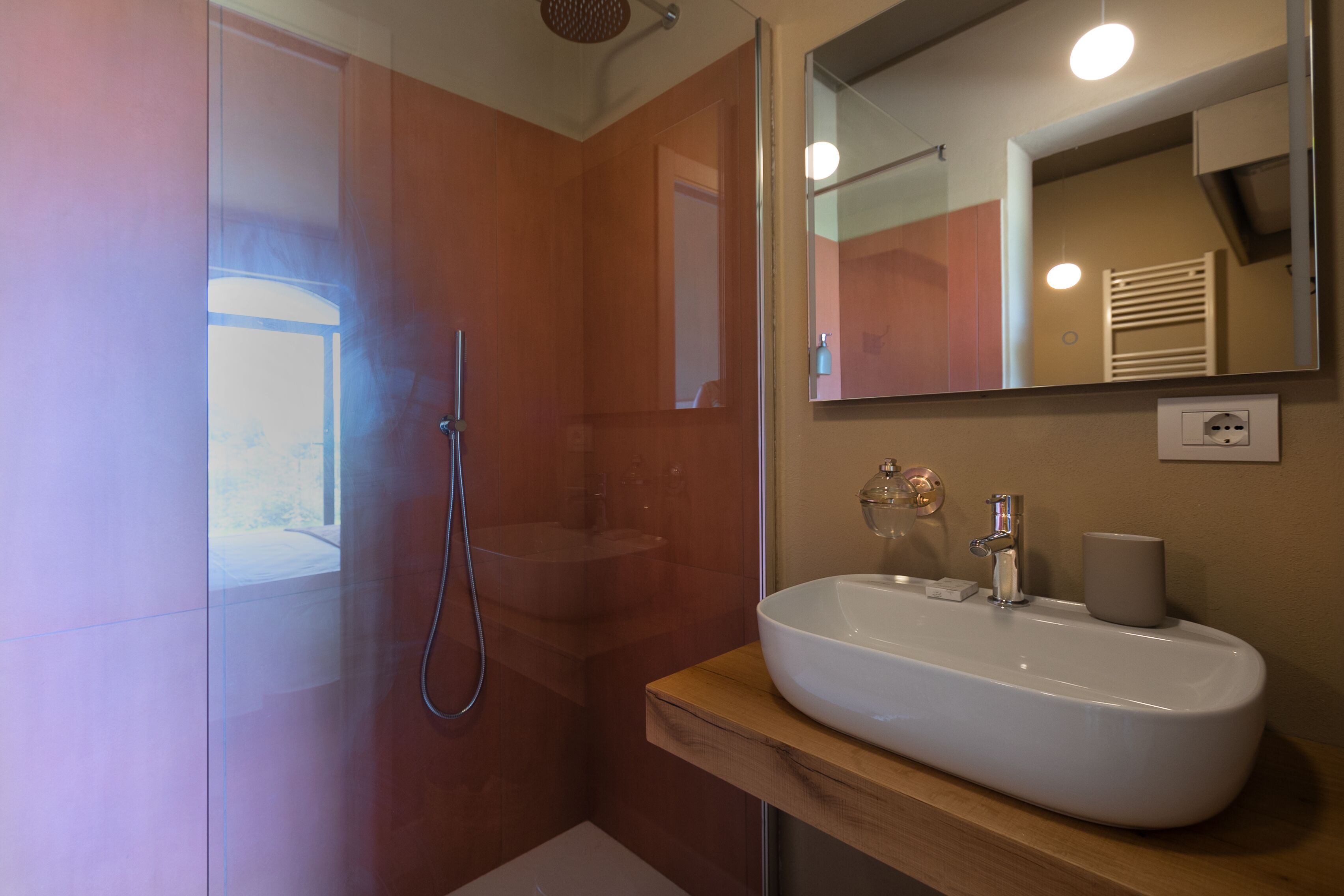 Une salle de bain moderne avec une douche à parois de verre, un lavabo blanc et un miroir au-dessus.