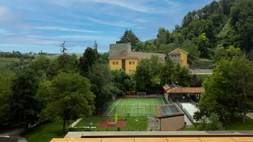 Ett bostadsområde med en tennisbana, ett gult hus och omgivande grönska.