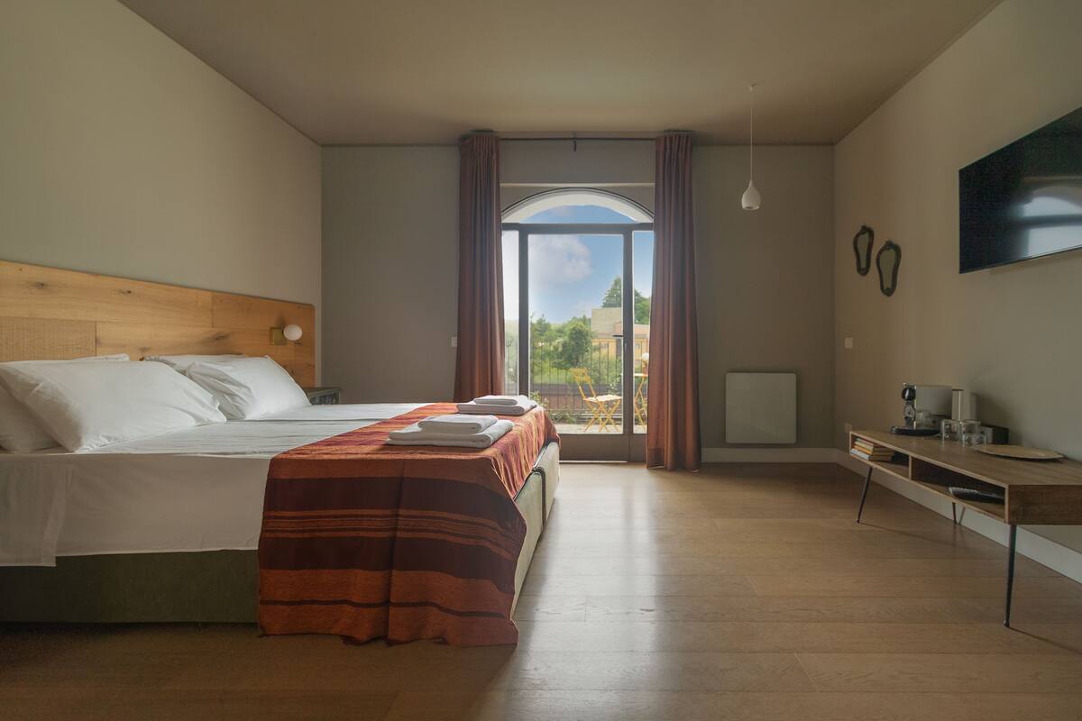 A bedroom with a bed, a desk, and a TV on the wall.