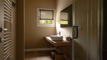 A bathroom with a wooden vanity, a white sink, a mirror, and a window with blinds.