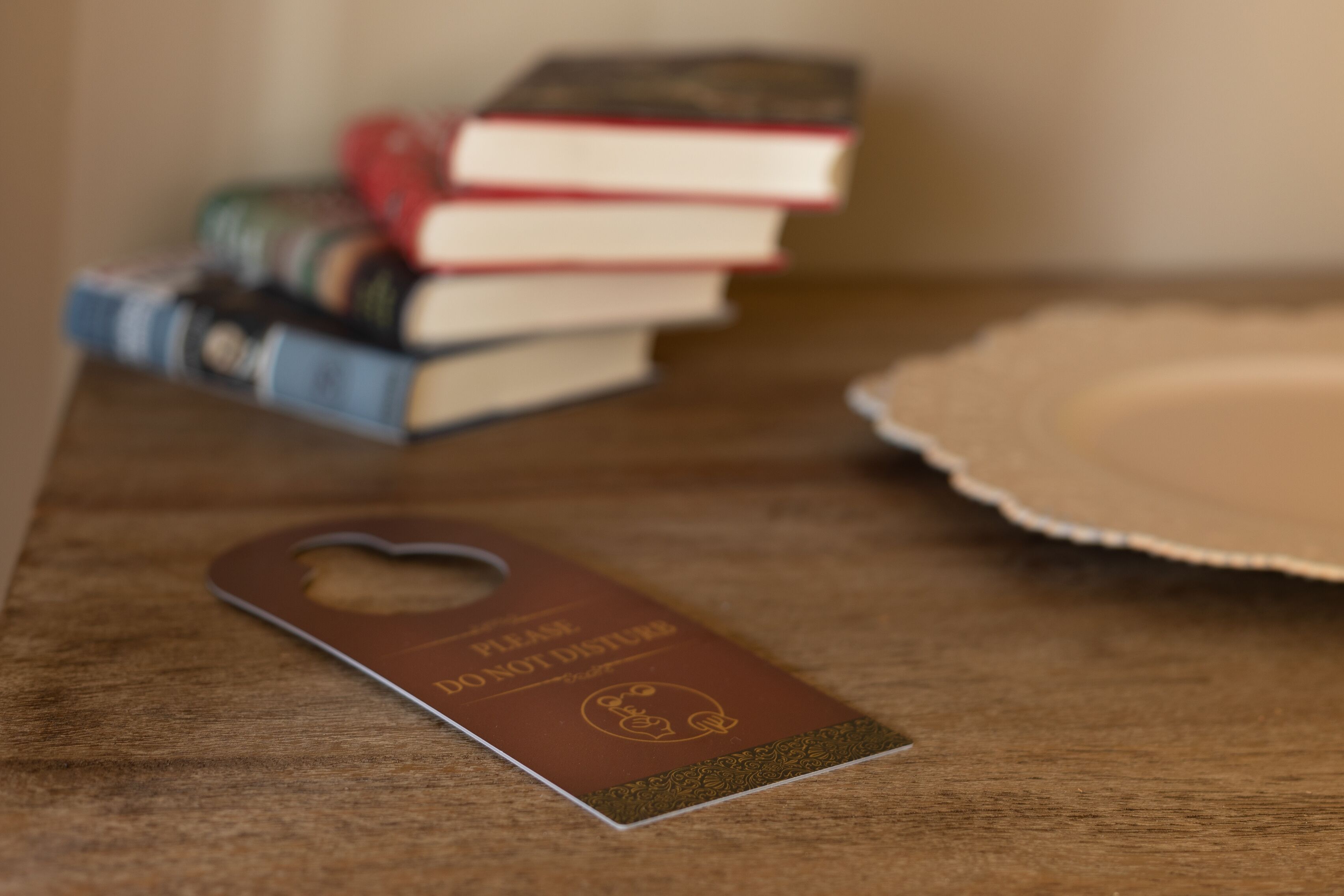 Une table en bois avec une étiquette marron, une pile de livres et une assiette blanche.