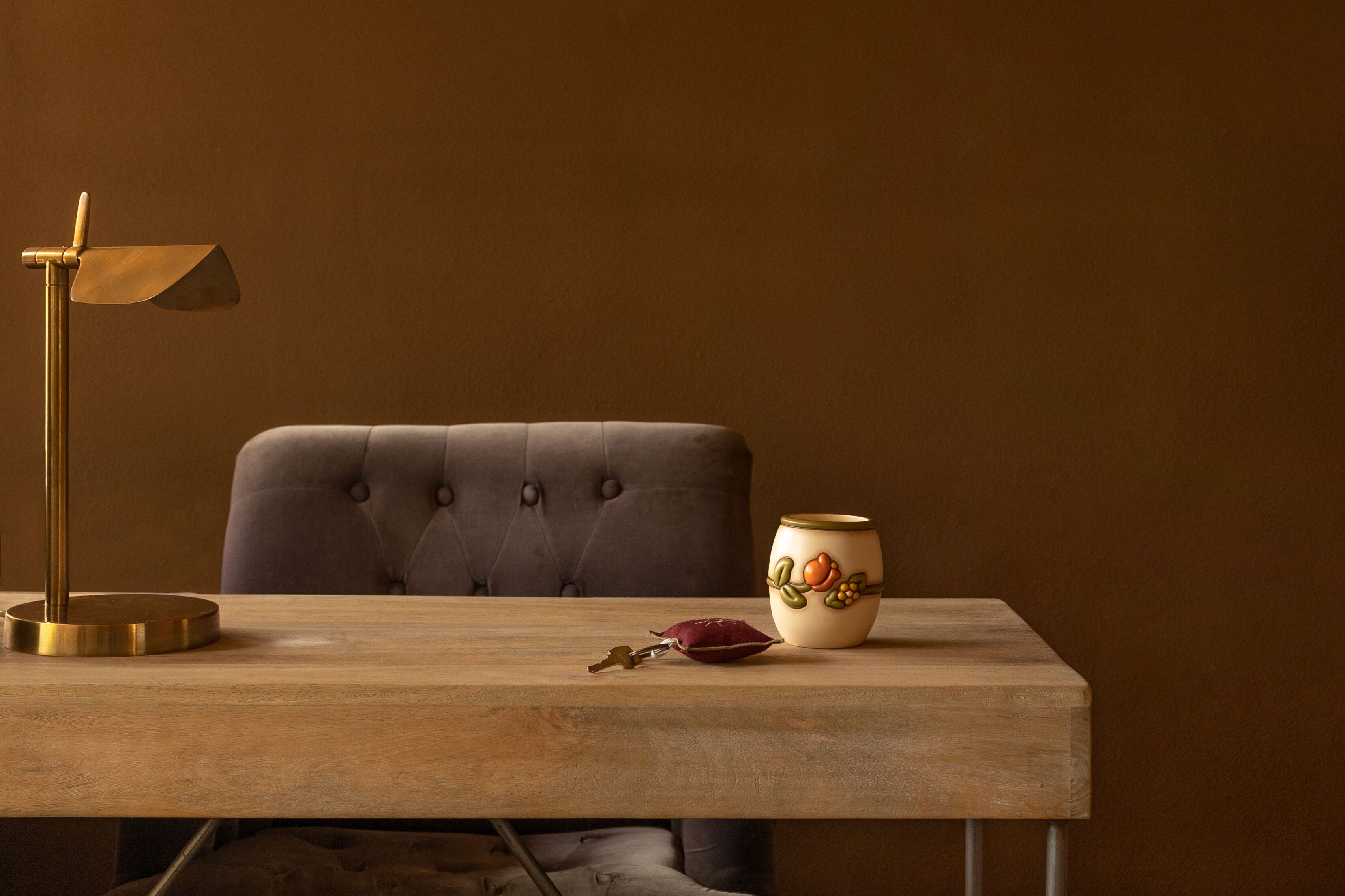 A wooden table with a lamp, a vase, and a key.