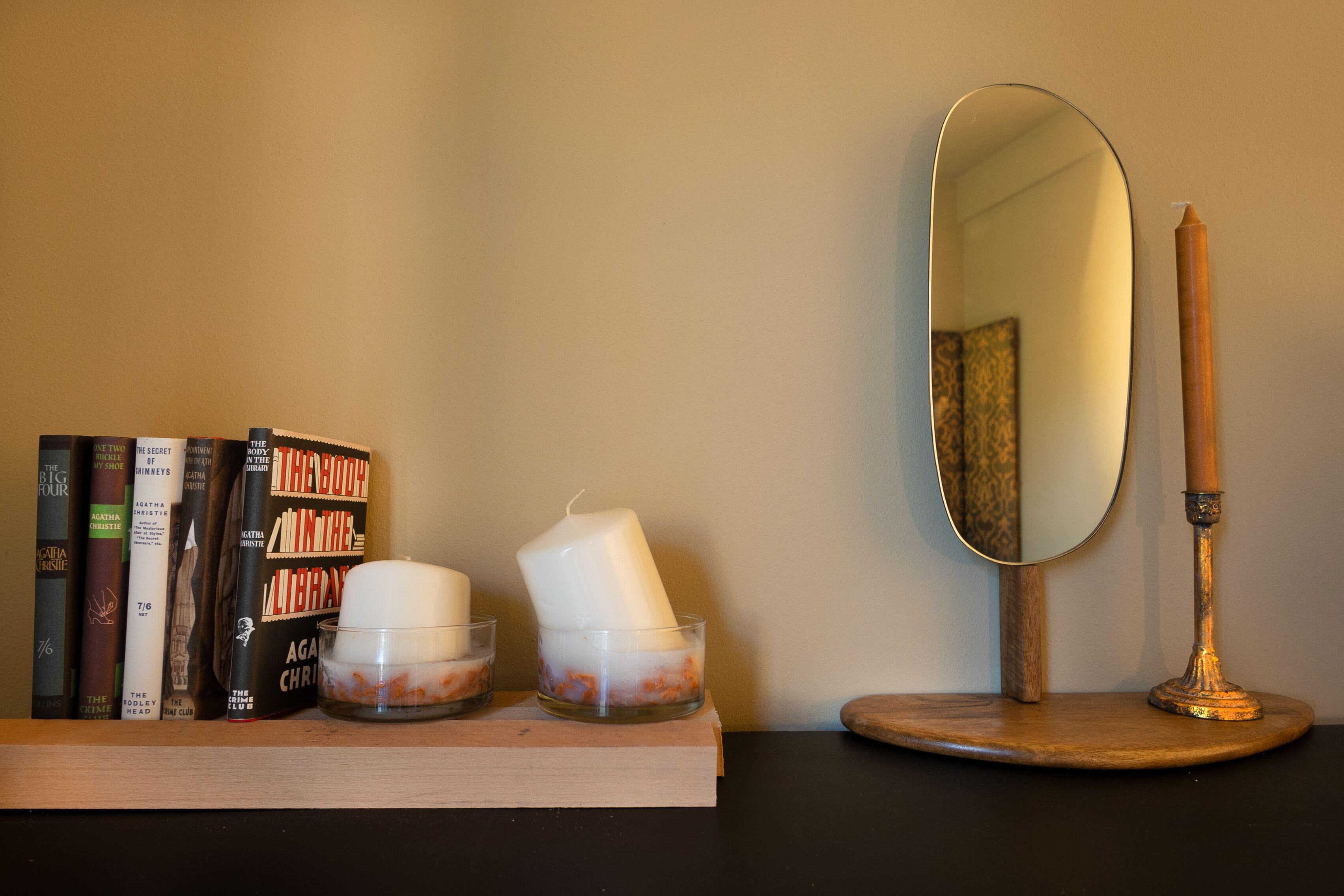 Ein Regal mit Büchern, Kerzen und einem Spiegel.