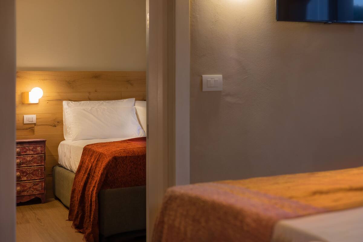 A room with a bed, a wooden headboard, a nightstand, and a wall-mounted TV.