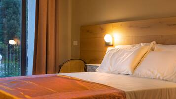 Ein Hotelzimmer mit hölzernem Kopfteil, einem Bett mit weißer Bettwäsche, einem Nachttisch und einem Sessel.