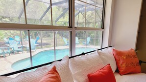 A bedroom with a view of a swimming pool and outdoor seating. - Family-sized beach house with pool; walk to beach and restaurants (St. Augustine)
