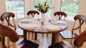 A round dining table with white plates, clear glasses, and a potted plant in the center. - Family-sized beach house with pool; walk to beach and restaurants (St. Augustine)