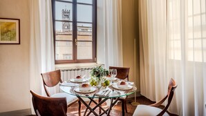 A dining table set for four with chairs, a window with curtains, and a radiator on the wall. - Antico Sogno Penthouse (Lucca)