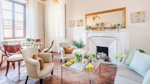 A living room with a fireplace, comfortable seating, and a dining area with a table set for four. - Antico Sogno Penthouse (Lucca)