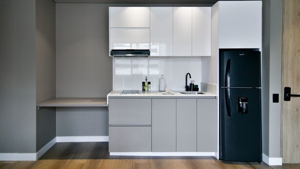A modern kitchen with grey cabinets, a black refrigerator, and a built-in oven.
