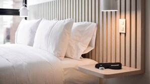 A modern hotel room with a neatly made bed, a bedside table with a lamp, and a wall-mounted light fixture. - w Magnificent Loft w City View in Santa Barbara (Bogotá)