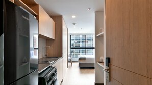 A modern kitchen with a black refrigerator, a stove, and a sink. There is a bed with a window in the background. - w Magnificent Loft w City View in Santa Barbara (Bogotá)