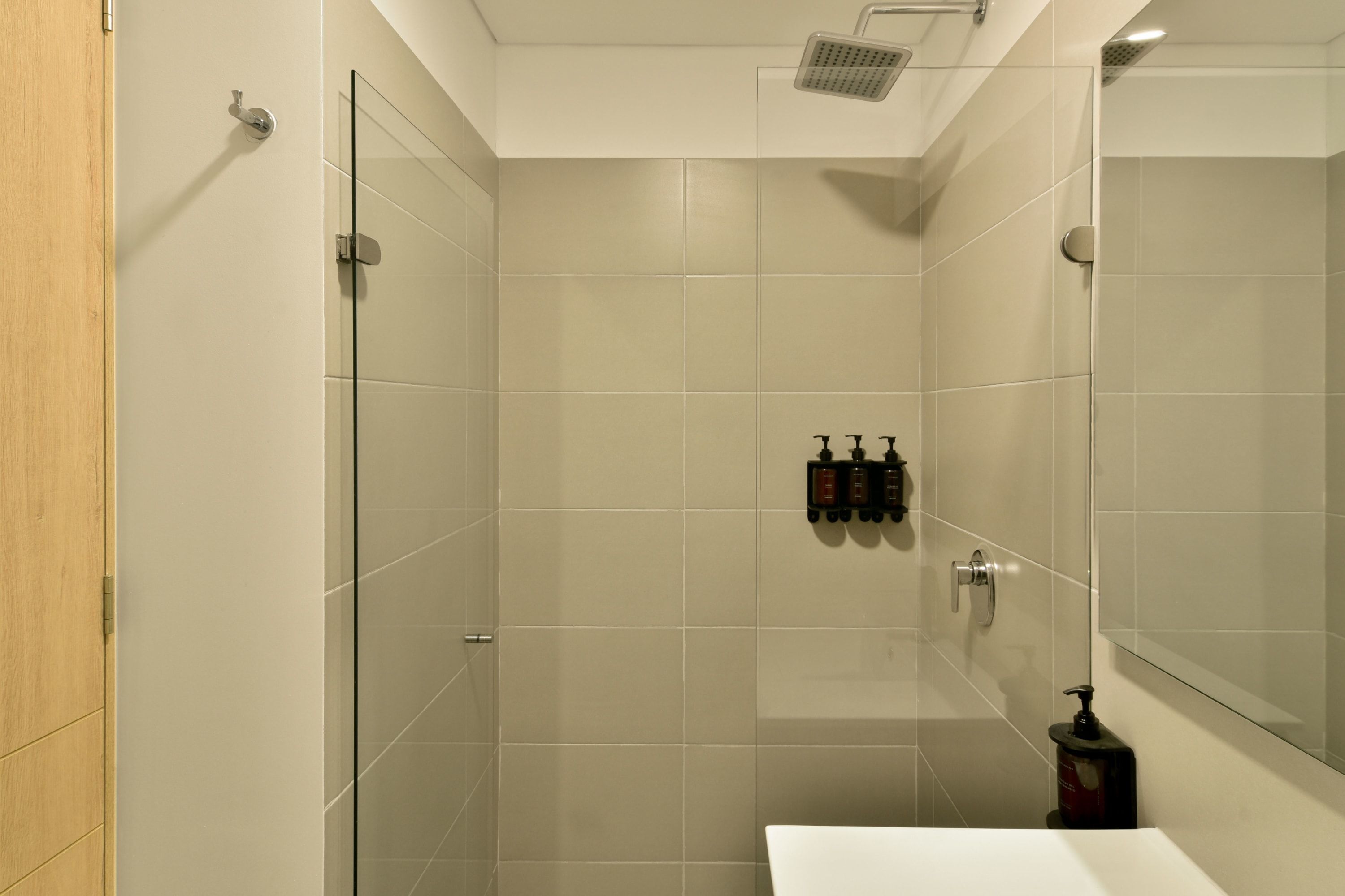 Een moderne badkamer met een douchecabine van glas, een witte wastafel en een spiegel.