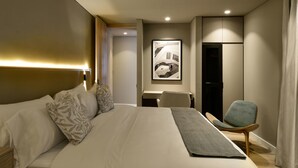 Habitació d'hotel amb un llit gran, una taula de treball, una cadira i un quadre al mur.