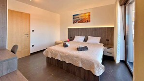 Et moderne hotelværelse med en stor seng, et skrivebord, en stol, et billede på væggen og et stort vindue.