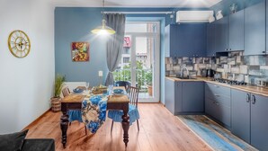A modern kitchen with grey cabinets, a wooden countertop, and a dining area with a blue tablecloth and wooden chairs. - HB apartments Mtskheta (Tbilisi)