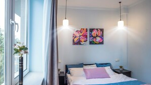 A bedroom with a bed, a window with a curtain, a vase with flowers, and two wall-mounted paintings. - HB apartments Mtskheta (Tbilisi)
