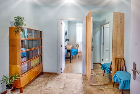 A hallway with a wooden cabinet, a potted plant, and a dining area with a table and chairs.