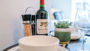 A dining table with a bottle of Chateau Cham, a salt and pepper shaker, a small potted plant, and a wine glass.