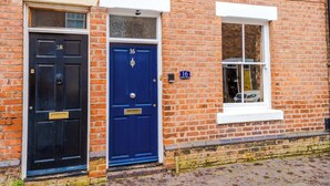 A brick building with two doors, one black and one blue, and a window with a white frame. - NEW! Stylish City Centre Home, Great Location! (Chester)