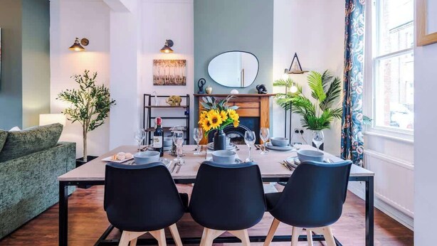 A dining area with a table set for three, a fireplace, and a large mirror above the mantel. - NEW! Stylish City Centre Home, Great Location! (Chester)