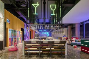 A bar area with neon signs, a swan decoration, and a colorful seating arrangement. - Moxy Ningbo Old Bund (Ningbo)