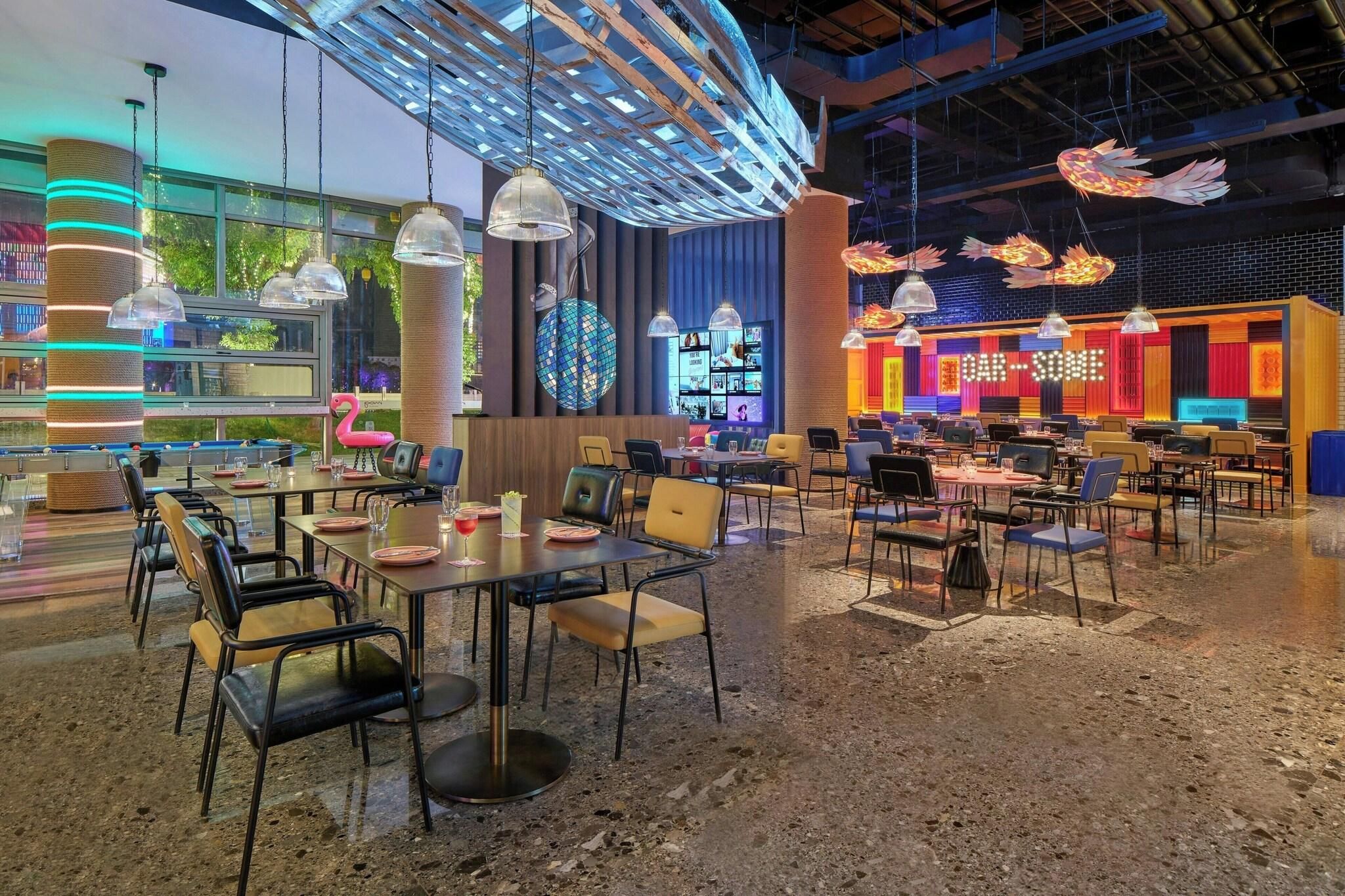 Un comedor interior amplio con varias mesas y sillas, un globo terráqueo grande y una exhibición vibrante en la pared.