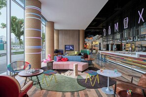 Eine moderne Bar mit Neonreklame, Sitzgelegenheiten und einem Fernsehbildschirm.