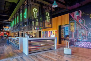 A modern bar area with neon signage, a reception desk, and a mural on the wall. - Moxy Ningbo Old Bund (Ningbo)