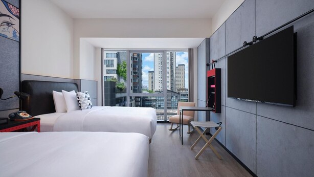 A modern hotel room with two beds, a TV mounted on the wall, a small table, and a chair. - Moxy Ningbo Old Bund (Ningbo)